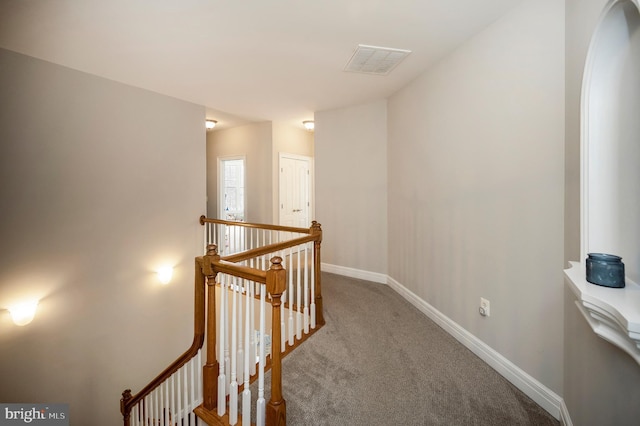 hall featuring an upstairs landing, carpet floors, and baseboards
