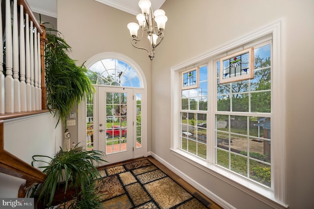 doorway featuring a chandelier, wood finished floors, baseboards, and ornamental molding