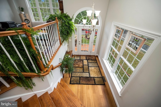 doorway to outside featuring a chandelier, wood finished floors, a high ceiling, and stairway