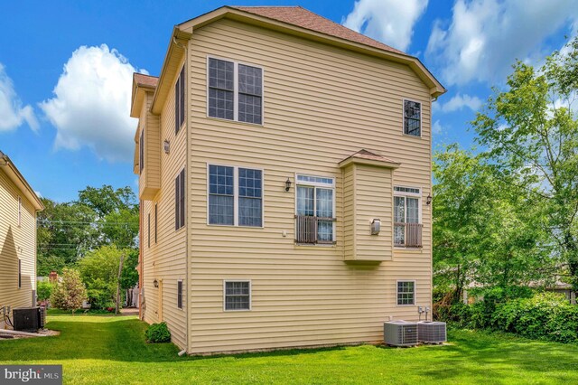 rear view of property with cooling unit and a yard