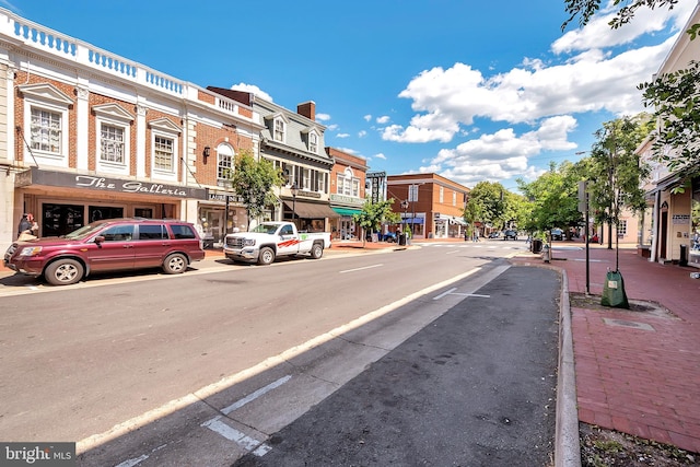 view of asphalt road with curbs, sidewalks, a residential view, and street lighting