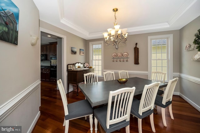 dining room with a raised ceiling, a chandelier, dark wood-style flooring, and crown molding