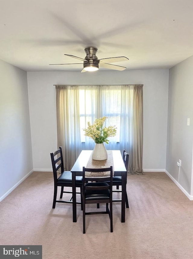 dining room featuring light carpet, baseboards, and ceiling fan