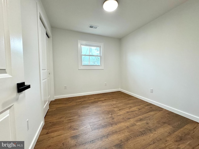 unfurnished bedroom featuring baseboards, a closet, dark wood finished floors, and visible vents