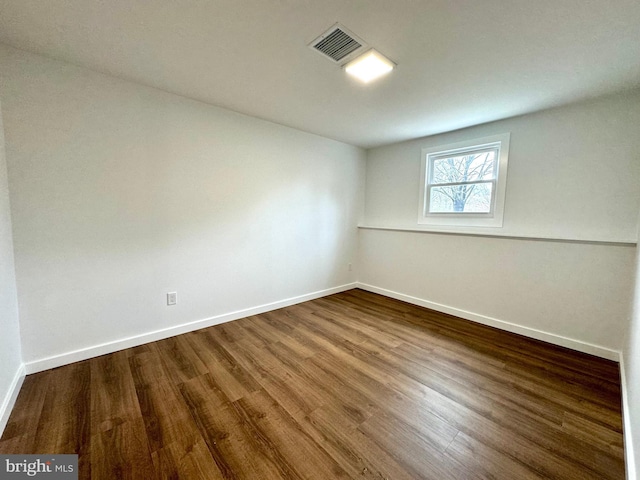 unfurnished room with baseboards, visible vents, and wood finished floors