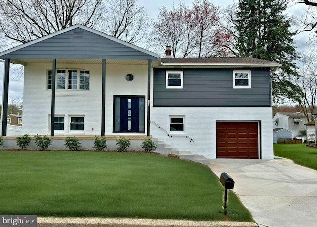raised ranch with an attached garage, concrete driveway, a chimney, and a front lawn