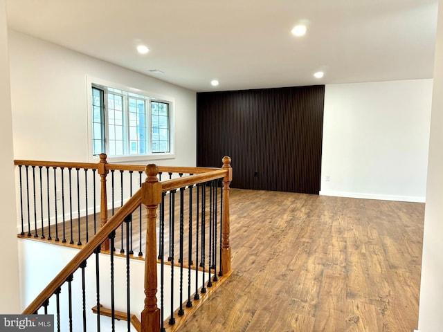 corridor with an upstairs landing, wood finished floors, baseboards, and recessed lighting