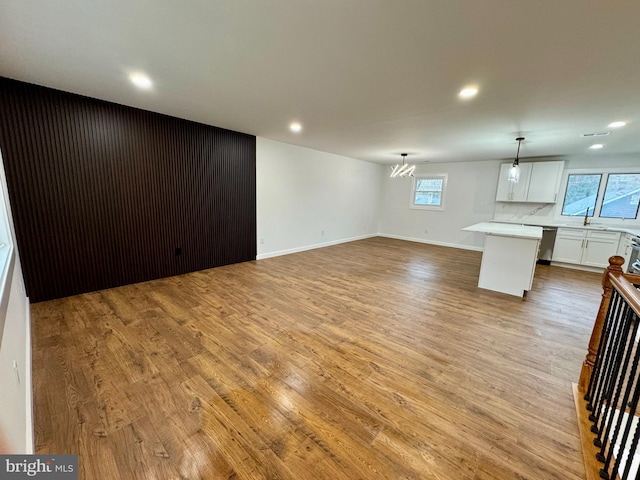 unfurnished living room with a wealth of natural light, light wood-type flooring, a chandelier, and recessed lighting