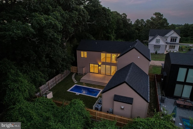 19690 Dunbar St, Rehoboth Beach, DE 19971 - back of property at dusk with a fenced backyard, a shingled roof, and a storage shed