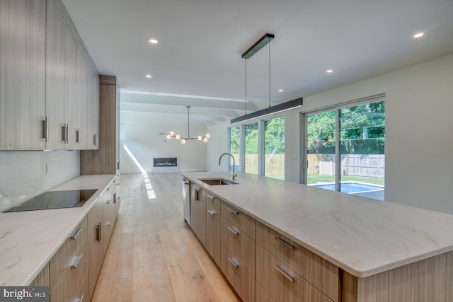 19690 Dunbar St, Rehoboth Beach, DE 19971 - kitchen with black electric cooktop, modern cabinets, light wood finished floors, a chandelier, and light stone countertops