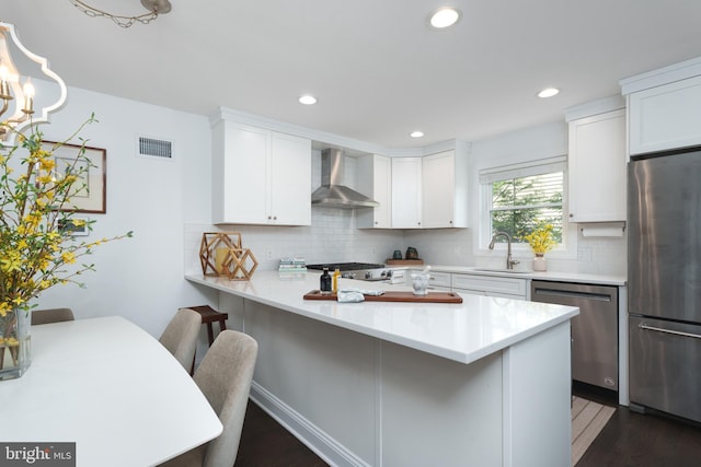 kitchen with a breakfast bar area, dark wood-style flooring, a sink, wall chimney exhaust hood, and stainless steel appliances