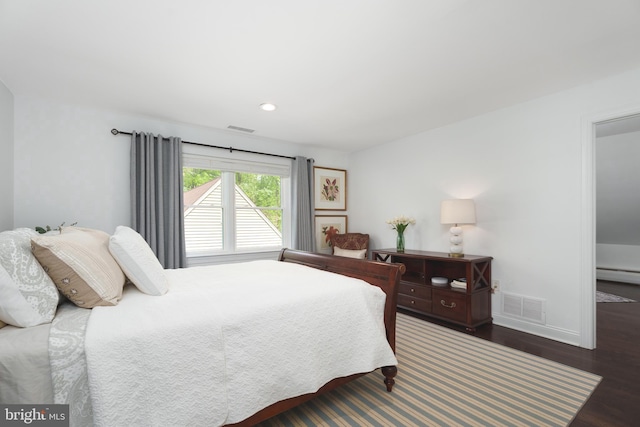 bedroom featuring baseboards, visible vents, wood finished floors, and a baseboard radiator