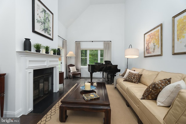living room with wood finished floors, baseboards, a glass covered fireplace, and high vaulted ceiling