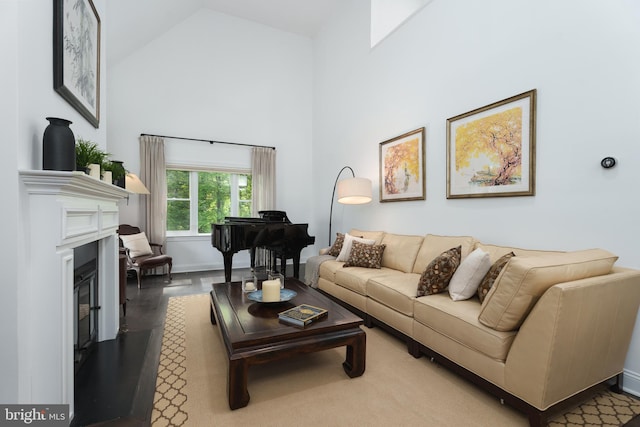 living area with high vaulted ceiling and a glass covered fireplace