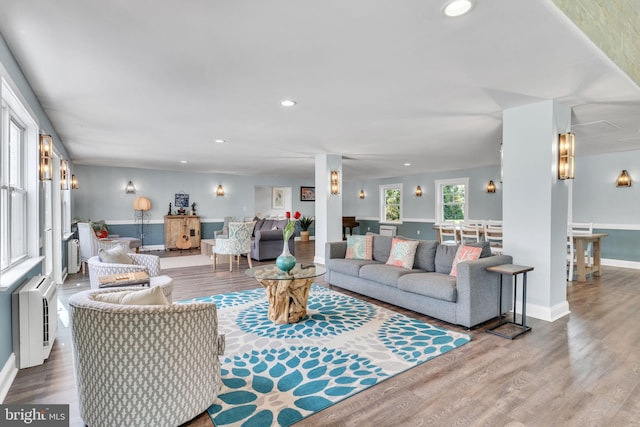 living room with heating unit, baseboards, recessed lighting, and wood finished floors