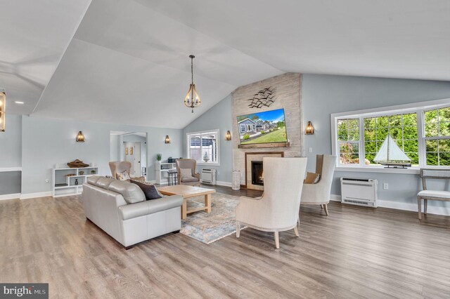 living area featuring lofted ceiling, heating unit, an inviting chandelier, wood finished floors, and a large fireplace