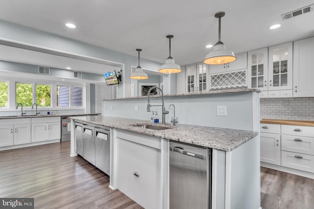 kitchen featuring a sink, tasteful backsplash, wood finished floors, visible vents, and white cabinetry