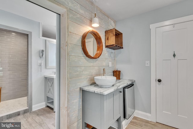 full bathroom with wood finished floors, baseboards, walk in shower, decorative backsplash, and vanity