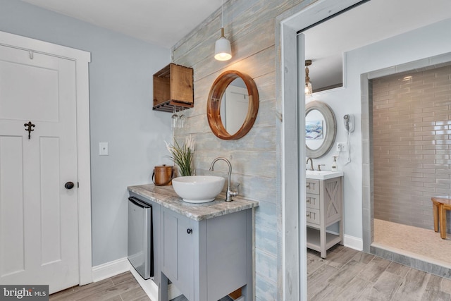 full bathroom with baseboards, wood tiled floor, two vanities, and a sink