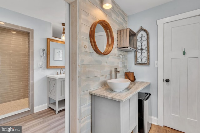 full bathroom with two vanities, a sink, and wood finished floors
