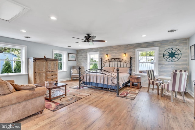 bedroom featuring multiple windows, light wood finished floors, and an accent wall