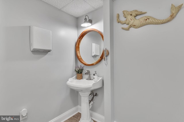 bathroom with baseboards and a drop ceiling