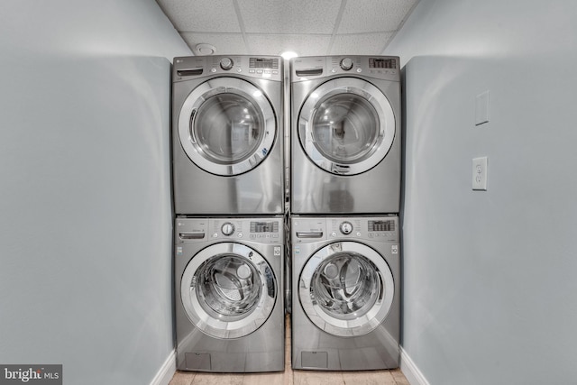 washroom featuring baseboards, laundry area, stacked washer / dryer, and washer and clothes dryer
