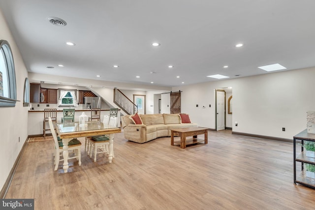living area featuring baseboards, stairs, light wood-style floors, and a barn door