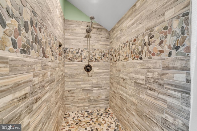 bathroom with vaulted ceiling and tiled shower