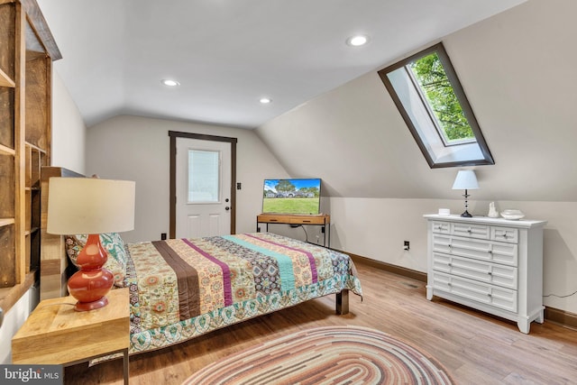 bedroom with baseboards, lofted ceiling with skylight, recessed lighting, and wood finished floors