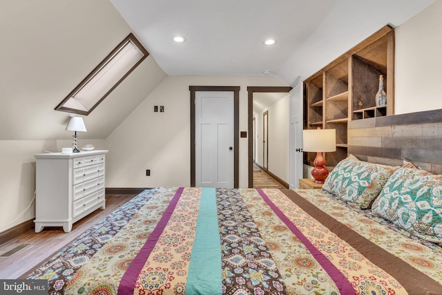 bedroom with wood finished floors, vaulted ceiling with skylight, visible vents, baseboards, and recessed lighting