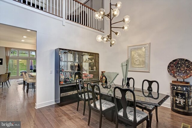 dining space featuring dark wood finished floors, baseboards, a towering ceiling, and a chandelier