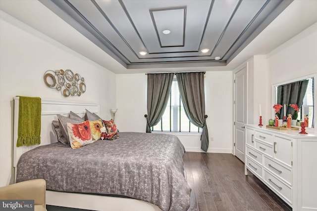 bedroom with dark wood finished floors, a tray ceiling, baseboards, and recessed lighting