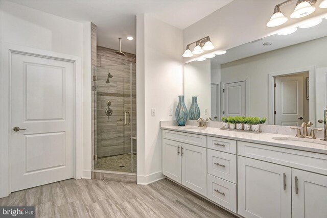 bathroom with a shower stall, double vanity, baseboards, and recessed lighting