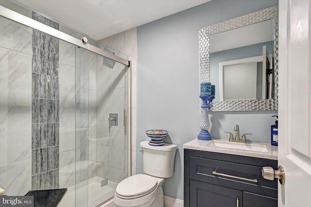 bathroom with a stall shower, toilet, vanity, and baseboards