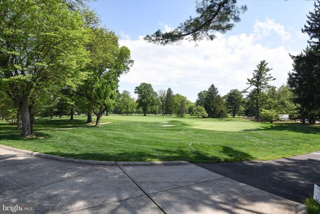 view of property's community with a yard, view of wooded area, and golf course view