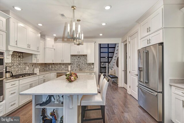 kitchen featuring stainless steel appliances, a breakfast bar, white cabinets, and recessed lighting