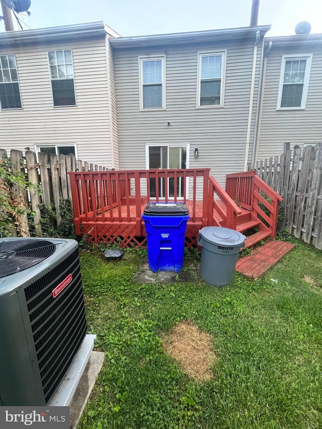 back of property with central AC unit, a deck, a yard, and fence