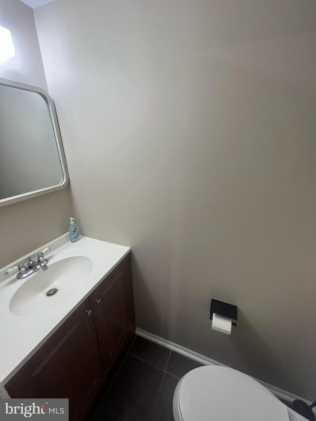 half bathroom with toilet, baseboards, tile patterned flooring, and vanity