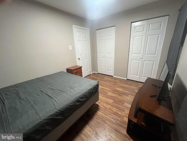 bedroom with two closets and wood finished floors
