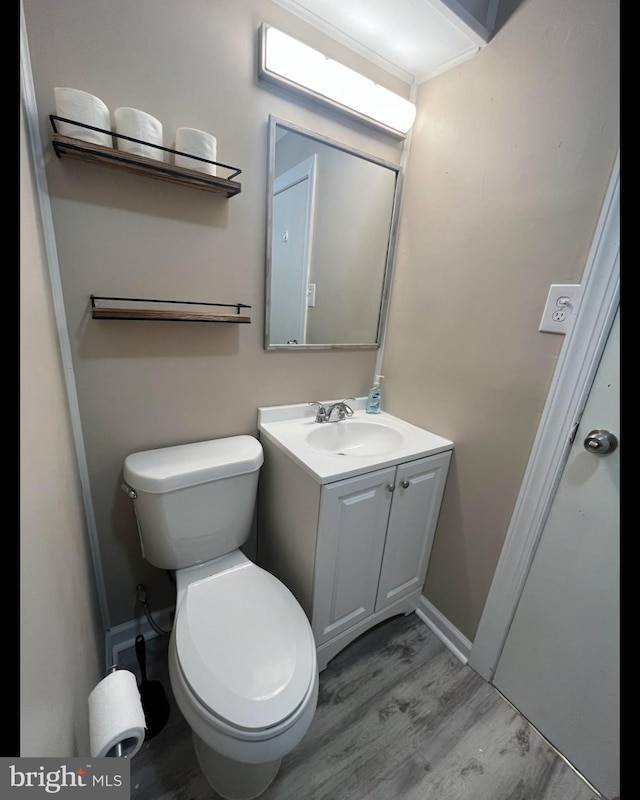 bathroom with toilet, baseboards, wood finished floors, and vanity