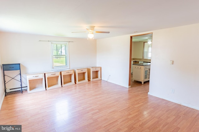 spare room featuring light wood-style flooring, a ceiling fan, baseboards, and baseboard heating