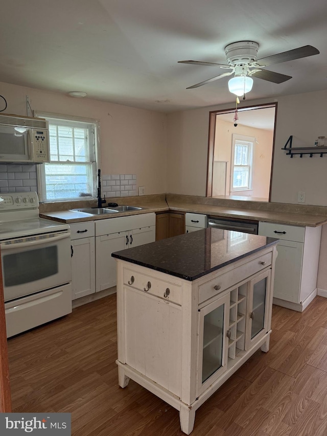 kitchen featuring white appliances, a sink, wood finished floors, and plenty of natural light