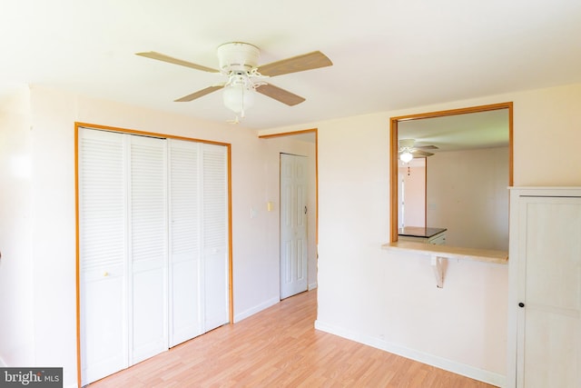 unfurnished bedroom with light wood-type flooring, a closet, baseboards, and ceiling fan