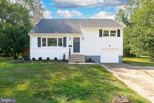 split level home featuring concrete driveway, a chimney, a garage, and a front yard
