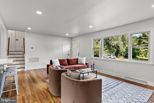 living area featuring baseboards, light wood-style flooring, recessed lighting, and stairway
