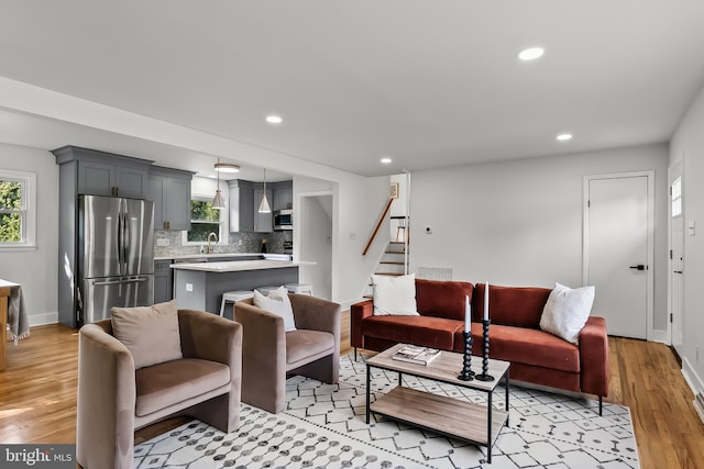 living area with stairway, recessed lighting, light wood-style flooring, and baseboards