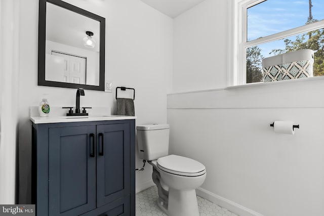 half bath featuring toilet, vanity, baseboards, and tile patterned floors