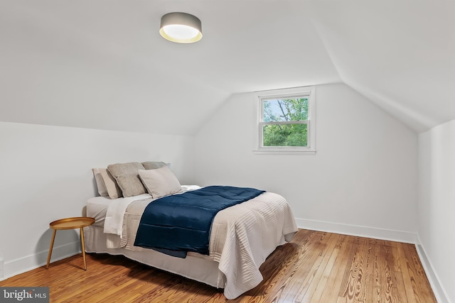 bedroom with wood-type flooring, baseboards, and lofted ceiling