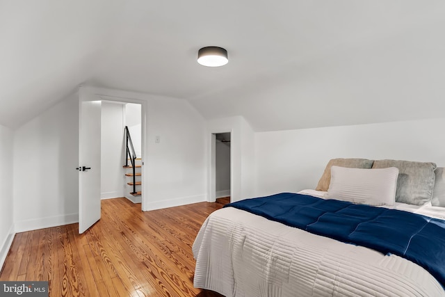 bedroom with vaulted ceiling, baseboards, light wood-style floors, and a closet